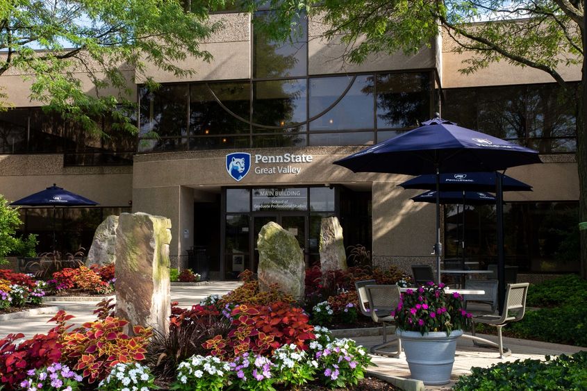 The entrance of Penn State Great Valley's Main Building, framed by trees and flowers