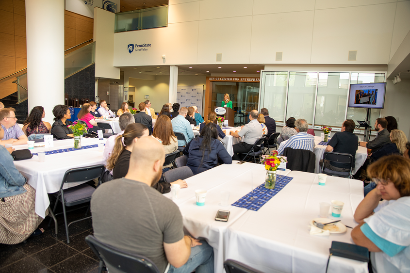 A group of people sitting at tables listening to a speaker